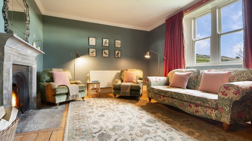 The sitting room with stone fireplace and open fire at Housesteads, Northumberland